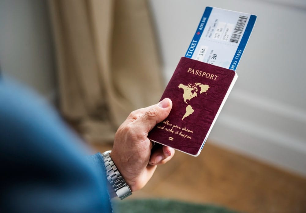 Hand holding a passport with a boarding pass, symbolizing international travel or immigration, resembling a Canadian travel document