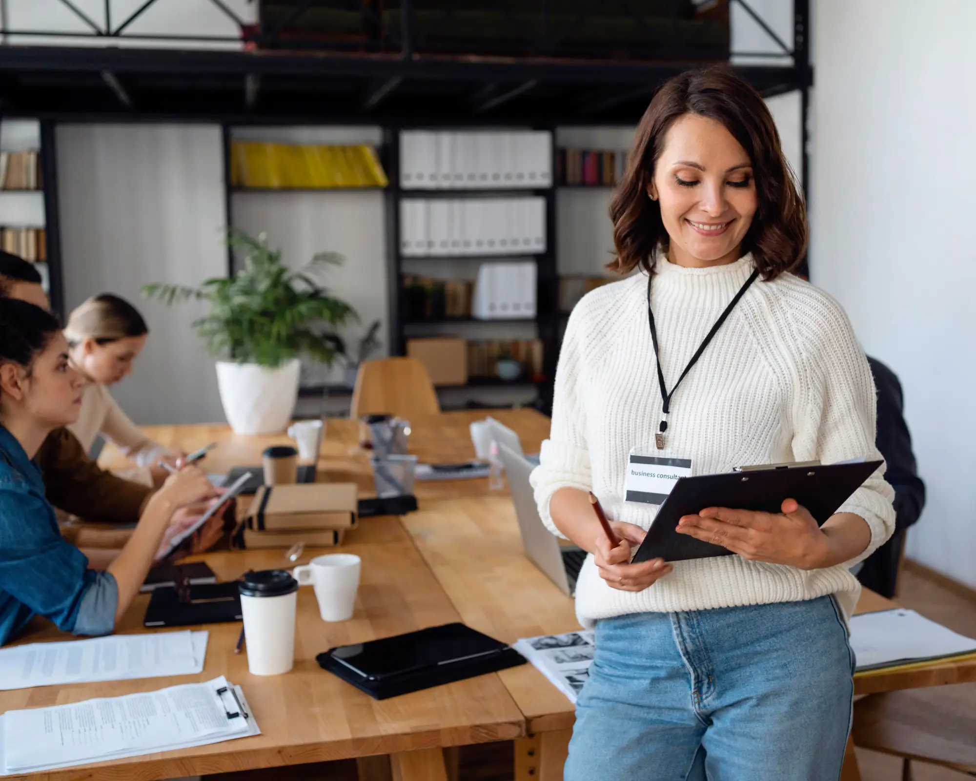 Woman holding clipboard in an office setting, representing applicants in Canada working under a Bridging Open Work Permit while awaiting permanent residency decision