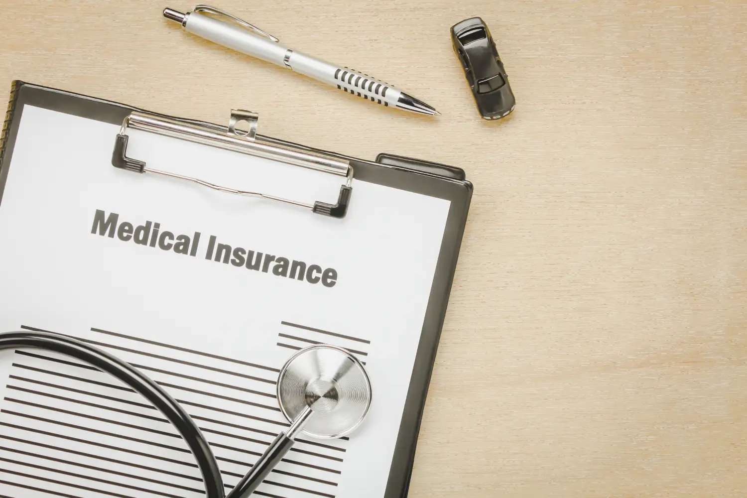 Medical insurance form with stethoscope and pen on wooden desk representing health coverage requirements