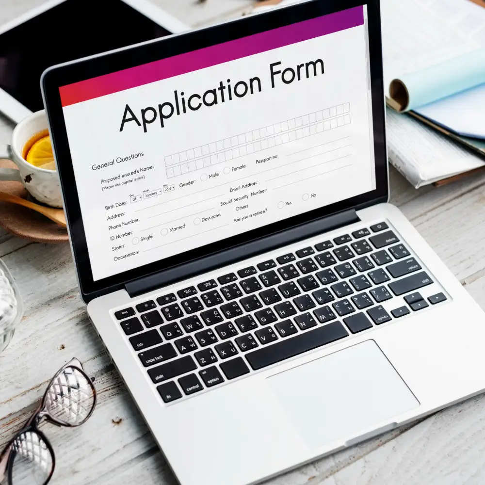 submitting visa application form with documents and laptop on desk
