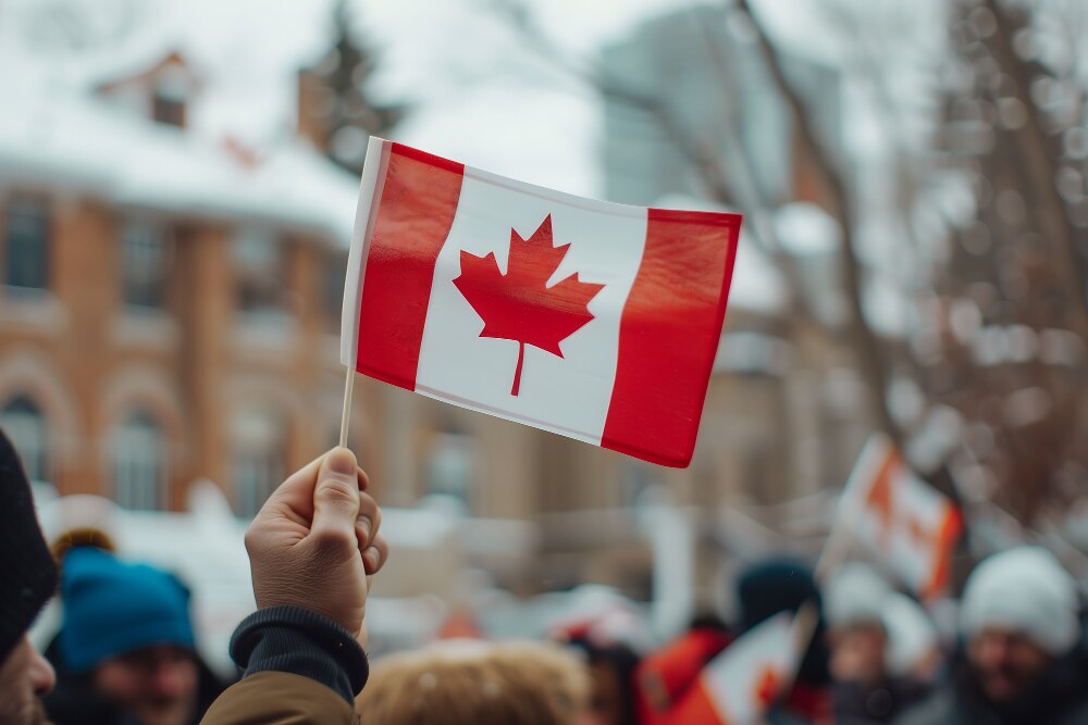 Person holding a Canadian flag during a winter public gathering